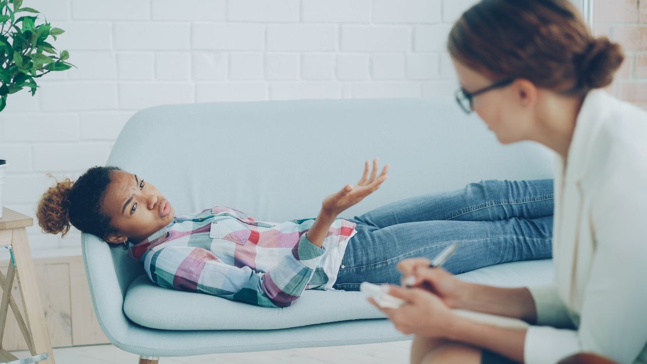Home A therapy session with a psychologist and a patient on a sofa, focusing on emotional well-being.