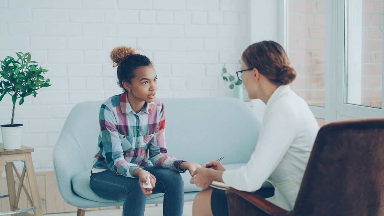 Home A teenager and therapist having a counseling session in a bright, modern office setting.