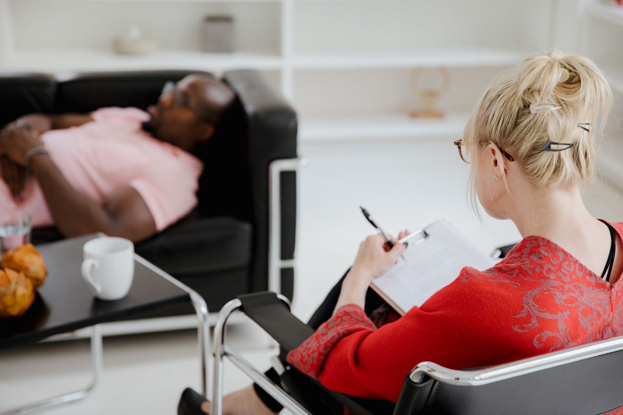 Home A professional therapist takes notes during a therapy session, engaging with a client.